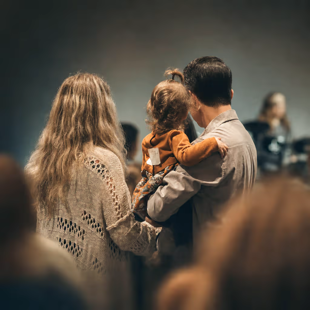 A family worshipping together, parents holding their young child